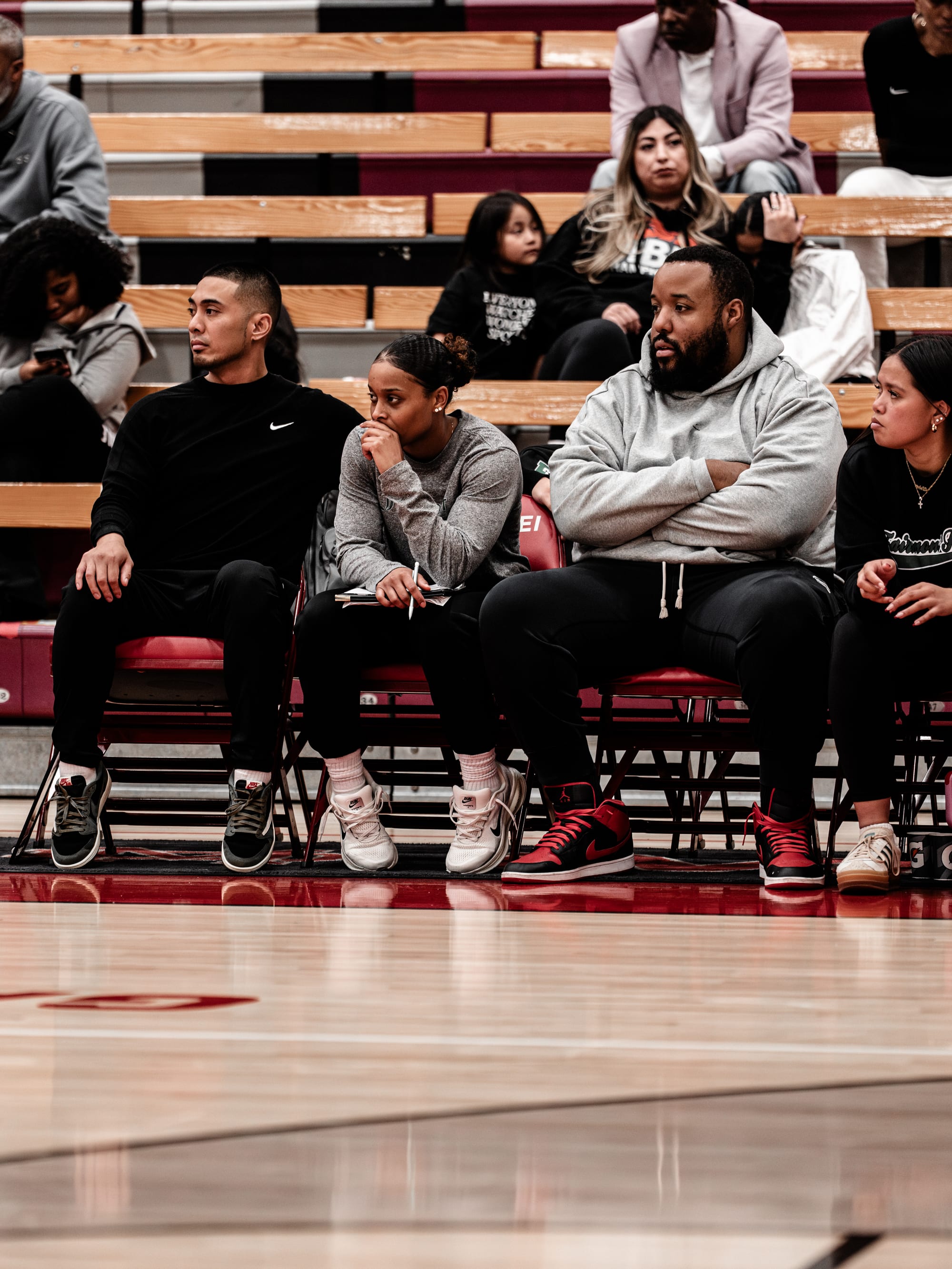 Coach Josh, Coach Asia, Coach Vic, and staff watching a game from the bleachers